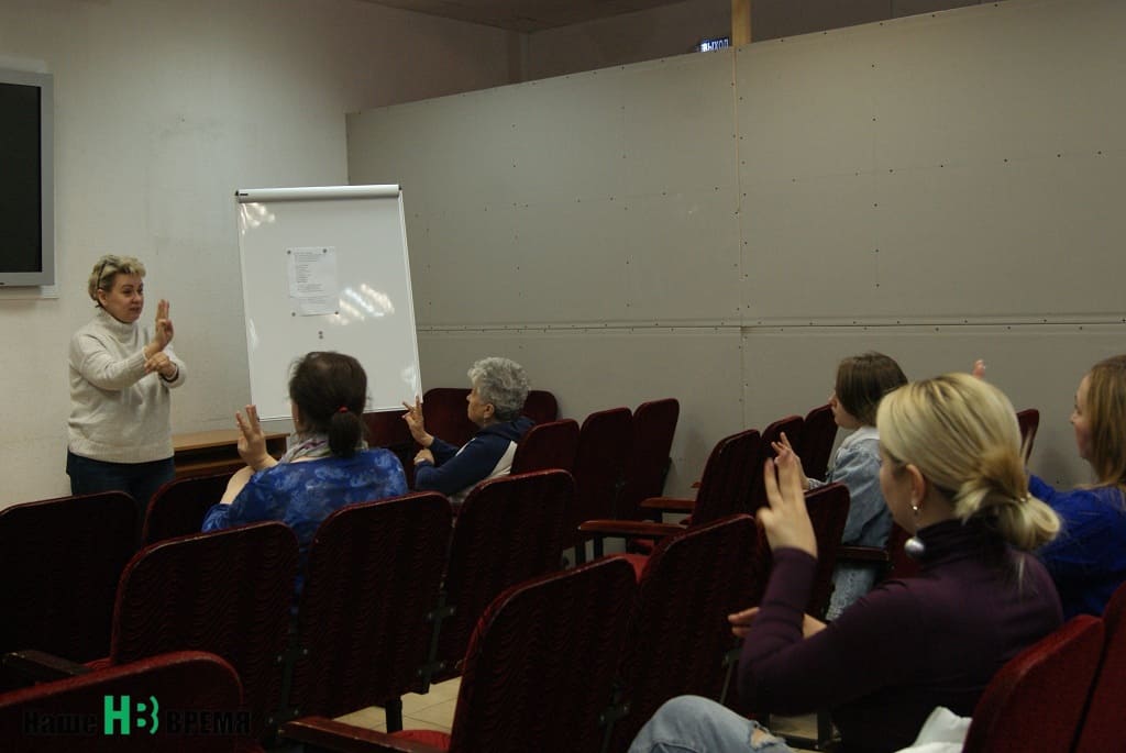 Рита Денисенко, заместитель руководителя регионального отделения ВОГ, специалист по русскому жестовому языку и по совместительству хормейстер группы ведет репетицию с членами ВОГ и теми, кто решил присоединиться к исполнению песни «День Победы» на жестовом языке.