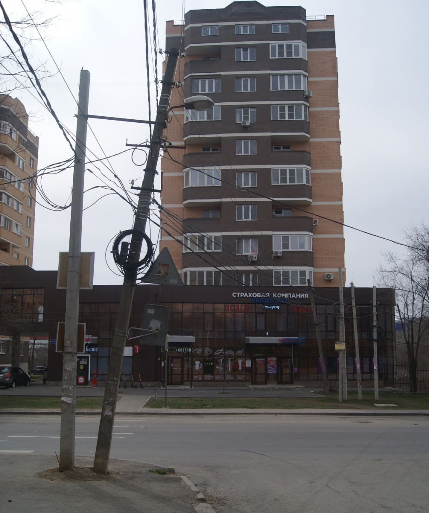 Бульвар Комарова. Одна из спорных опор наклонена. От опоры провода идут к новостройке и вправо от нее — к ГСК «Родник».