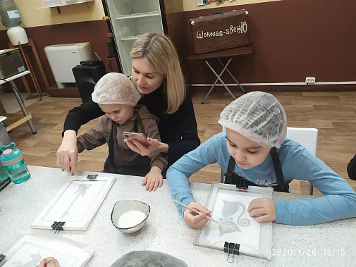 Екатерина Колодяжная делает поделку из шоколада. А Гордею Громову в этом помогает мама Анна.