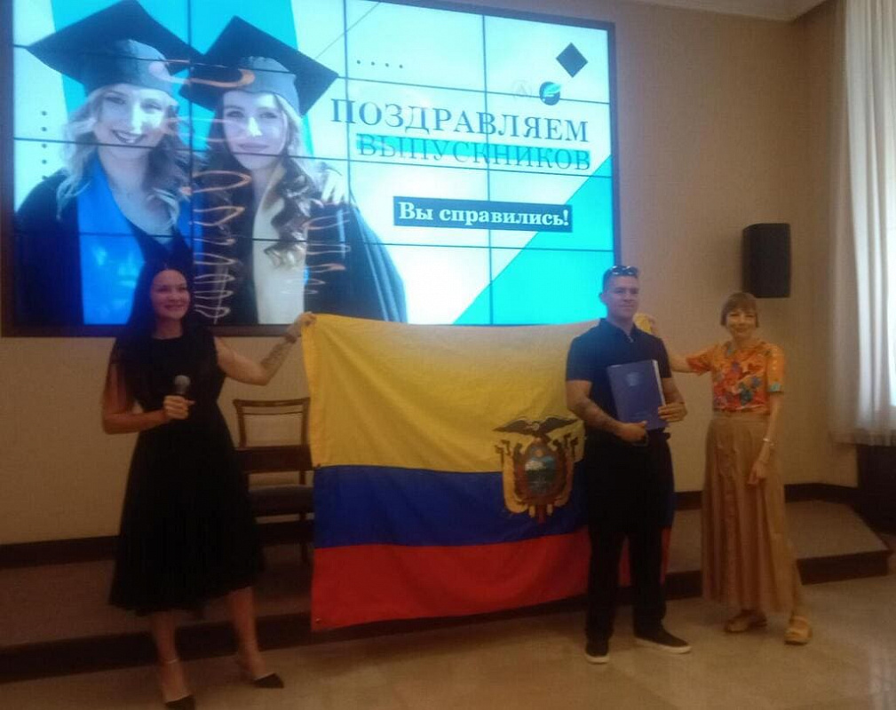 Вручение диплома выпускнику из Эквадора на фоне флага его страны
