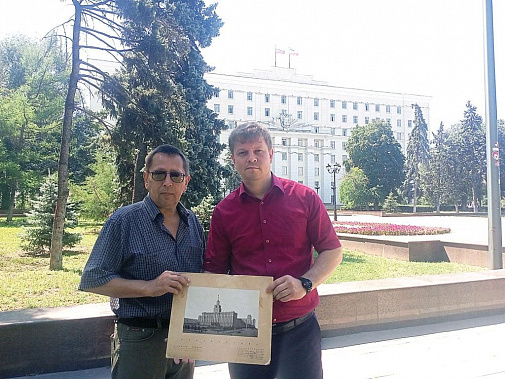 Алексей ЗАХАРОВ (слева) передает Сергею ГОРДИЕНКО фото здания, где сейчас располагается правительство Ростовской области. Раньше оно выглядело по-другому.